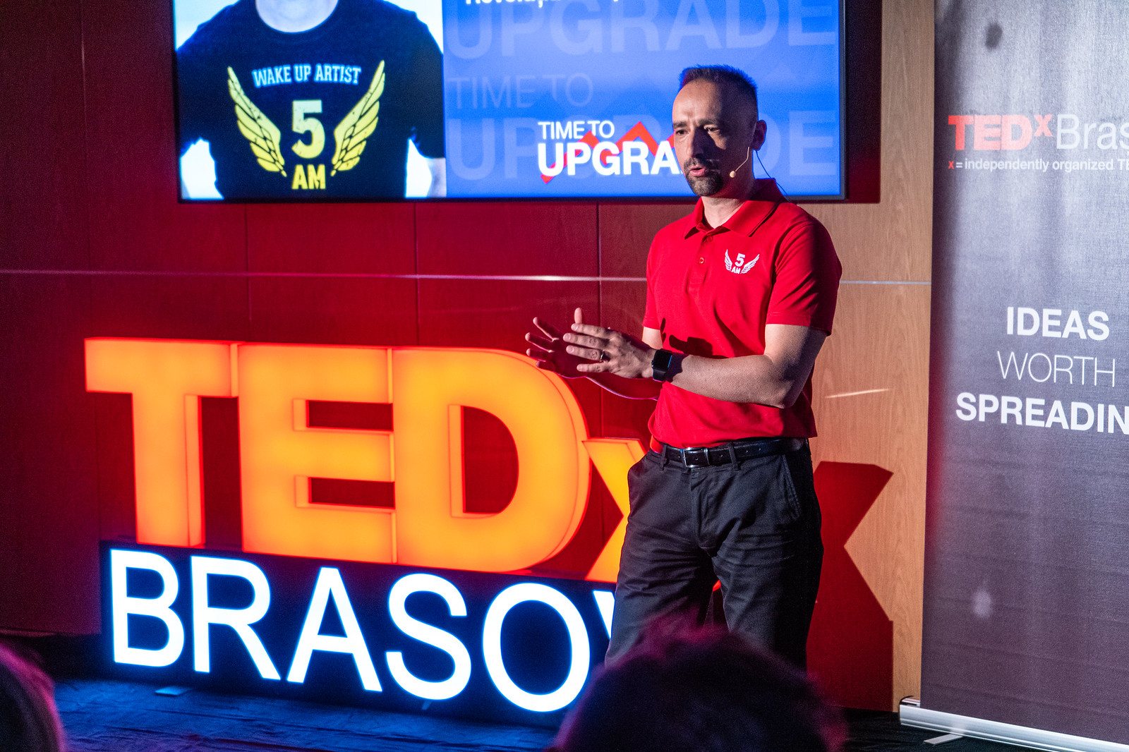 Dan Luca pe scena TEDx Brașov, în tricoul roșu 5AM